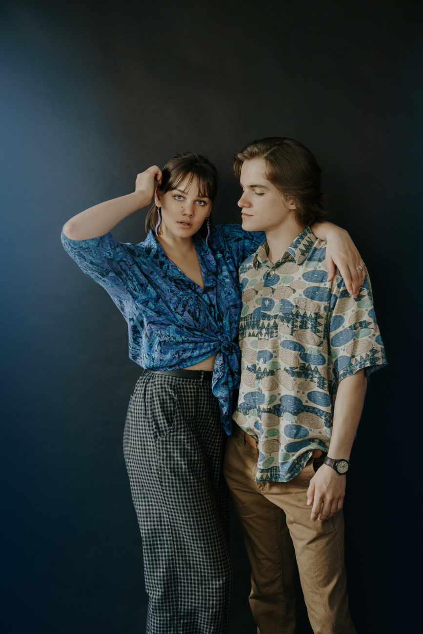 studio-engagement-session-with-couple-wearring-two-loud-patterns-blue-green-black-background