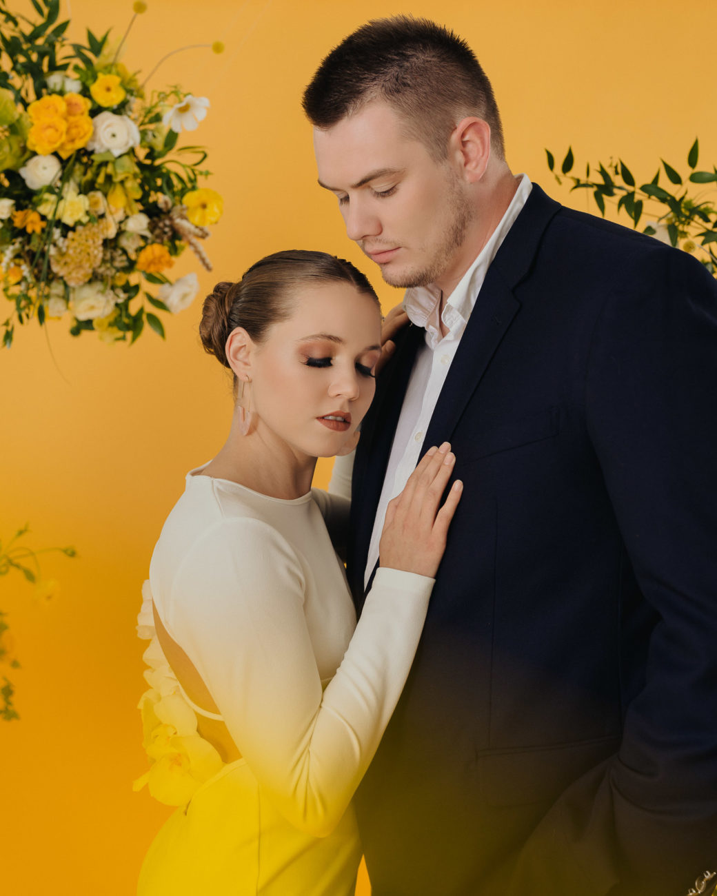 bride-and-groom-modern-wedding-attire-sleek-dress-flower-back-blue-suit-studio-yellow-backdrop-floating-floral-installation-tulsa-photographer